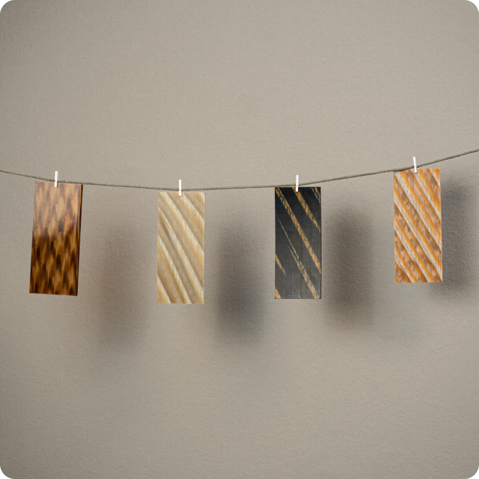 Four patterned eyeglass frames hanging on a line against a neutral background, showing woodgrain and striped designs.